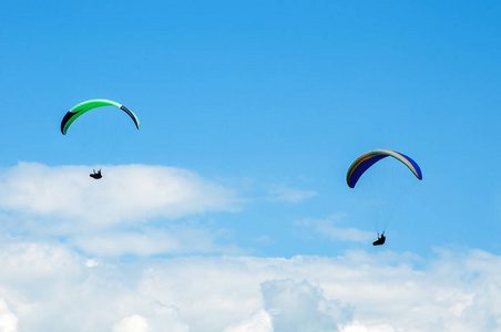 两个滑翔伞翱翔于蓝天的背景下云