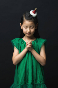 可爱的亚洲妇女祈祷圣诞节与头饰黑色背景和收集两只手的孩子