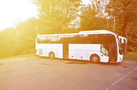 短途旅行的白色旅游巴士。公共汽车停在公园附近的停车场。