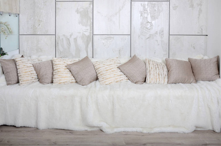 许多枕头躺在沙发上, 上面覆盖着一层巨大的毛绒面纱, 背景是大理石墙。
