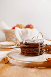 圆饼干与糖粉在圆的木板, 一篮子苹果, 白色毛巾在轻的背景周围的秋天叶子