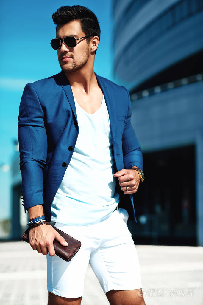 性感帅气的时尚男模特男子肖像身着优雅的西装摆在街头背景.蓝天