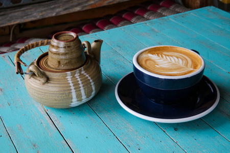 热的艺术拿铁咖啡和茶在一个杯子在蓝色木桌