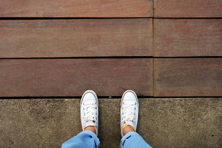 时尚女性在白色运动鞋与蓝色牛仔裤的木地板背景伟大的任何使用
