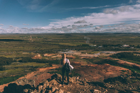 站在悬崖上, 看着在冰岛壮丽的景观年轻女子的背部视图