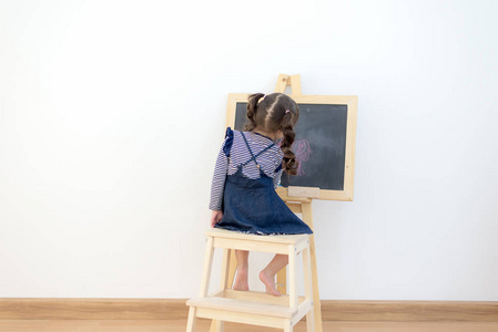 可爱的小女孩在家里画黑板。生活方式概念