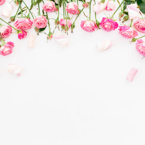 白色背景的粉红色玫瑰和棉花糖的花框。平躺, 顶部视图