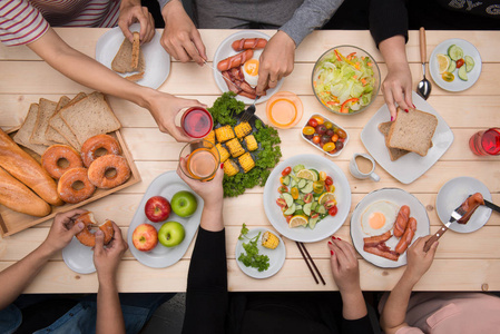 享受与朋友共进晚餐。顶视图的一群人一起坐在木桌吃饭