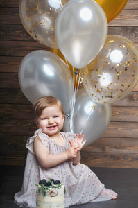 愉快的婴孩女孩与空气气球和蛋糕在生日党