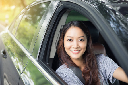 美丽的亚洲女人微笑，enjoying.driving 路上一辆车