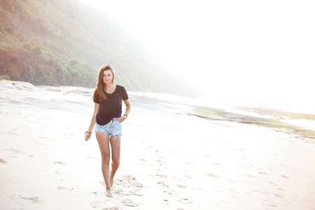 美丽的女人在黑 tshirt 走在沙滩上