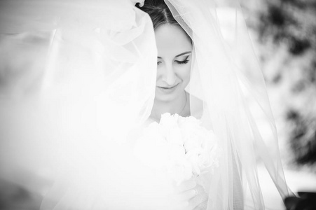 温柔的新娘在面纱, 幸福的女人在婚纱礼服与花束在手, 白色面纱盖面, 对比黑白