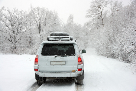 白雪皑皑的冬日道路后面，一辆面目全非的汽车