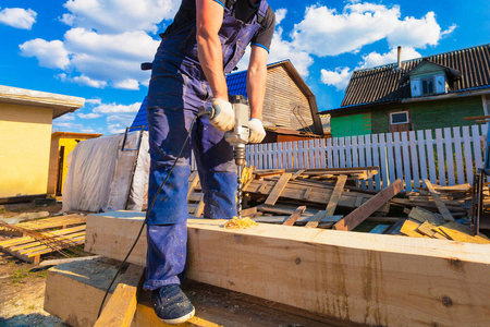 木匠 工人 用大的专业工具 电钻 在改建翻新扩建修复改建和施工中钻木梁