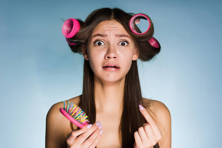 满意一个年轻的女孩没有时间去准备一个聚会, 做一个发型, 在她的头上一个大的粉红色夹, 保持梳子