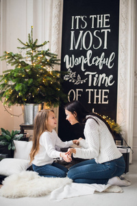 小女孩在针织毛衣的特写照片亲吻她的母亲, 而坐在沙发上的圣诞节