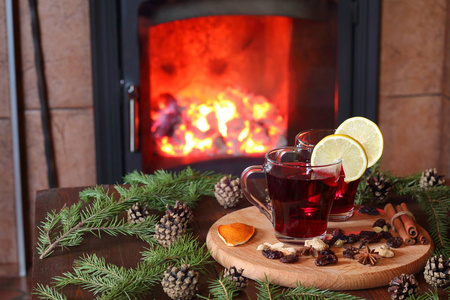 温热的酒在壁炉前的冷杉树枝之间的一张木桌上的一杯温热酒