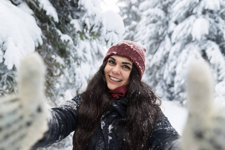 年轻美丽的女人微笑相机拍摄自拍照片在冬季雪森林女孩户外