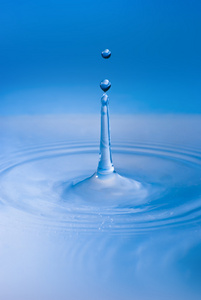 干净的蓝色水滴在清澈的水中飞溅。 抽象的蓝色