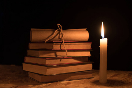 旧书 燃烧的蜡烛和滚动在木制的桌子上