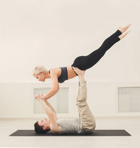 年轻夫妇在垫子上练习 acroyoga