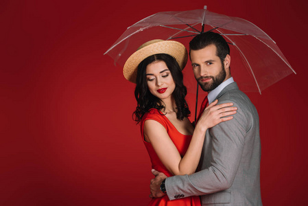 有吸引力的情侣拥抱在透明的伞下红色隔离