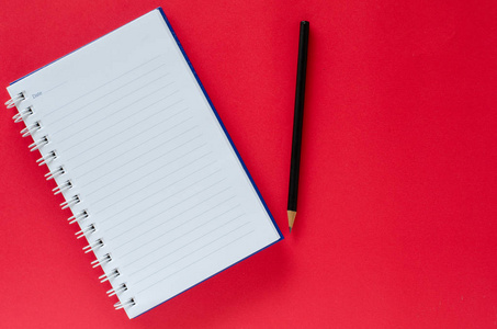白色的笔记本和 co 的红色背景上的黑色铅笔