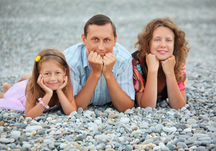 幸福的家庭和小女孩躺在石滩，专注于脂肪