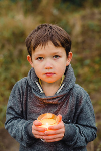 一支燃烧的蜡烛靠近一个孩子男孩的手
