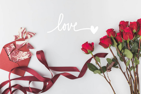 平躺在红色玫瑰与丝带和信封的安排与甜甜点隔离在白色, st 情人节概念