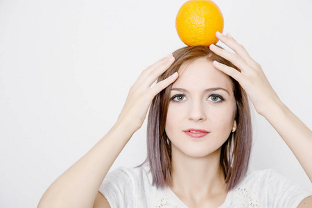 拿着橘子的女人年轻妇女与柑橘。橙色在女孩的头上