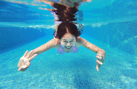 水下拍摄的年轻女人在游泳池里跳水