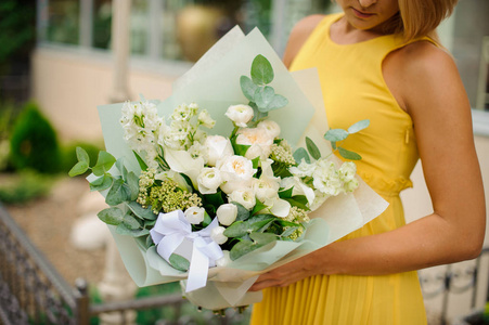 身穿黄色礼服的女子手持白色花束的 flowe