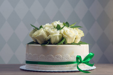 美丽的白色婚礼蛋糕装饰着花束白花白玫瑰。典雅假日甜点的概念
