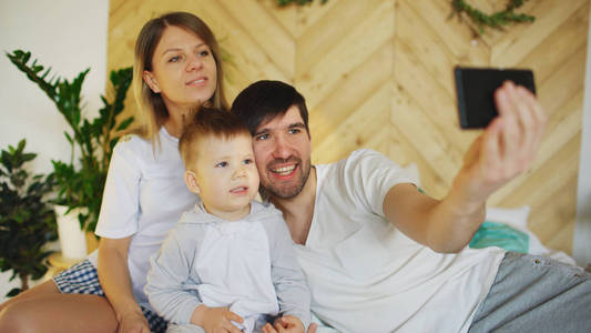 微笑的父母与宝宝合影拍照家庭在家里的床上