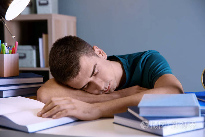 疲倦的学生睡在他的办公桌室内.准备考试
