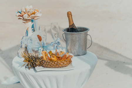 桌子上装饰着一瓶香槟, 凉爽, 眼镜和水果。热带海滩婚礼准备