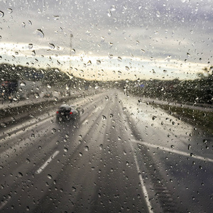 车窗上的雨滴在公路上开着模糊的路