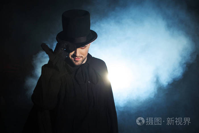 戴着黑色顶帽子和斗篷的男人恶魔般的形象魔术师魔法师