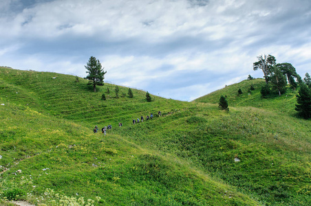 旅游集团在夏季的高山草原上徒步漫步在山脉中