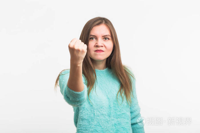 愤怒的年轻黑发女子显示拳头.这个女孩很生气, 准备用