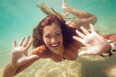 美丽的年轻女子潜水水下在海里。看相机