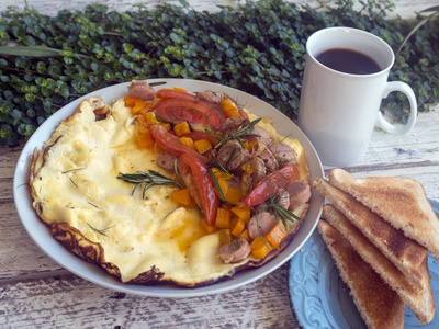 煎蛋卷, 蔬菜和香肠在木质的背景下。早餐