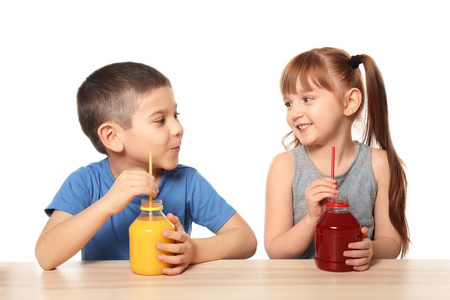 可爱的小孩子喝柑橘汁在桌上白色背景