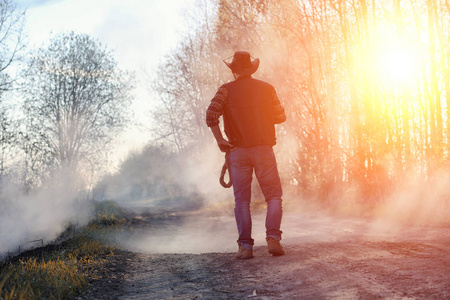 一个男人在田里戴着一顶牛仔帽和一 loso。美国