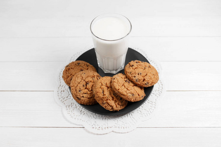美味的饼干和牛奶玻璃在质朴的白色木质背景