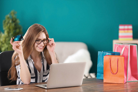 网上购物的年轻妇女与信用卡和笔记本电脑在桌上