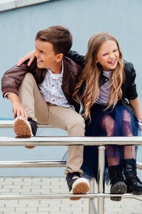 孩子们, 一个男孩和一个女孩坐在公园里的朋友的栏杆上。友情概念