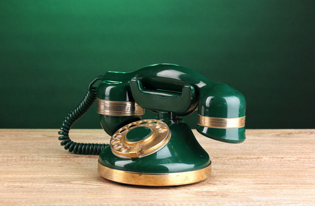 复古绿色背景上的木桌上的电话