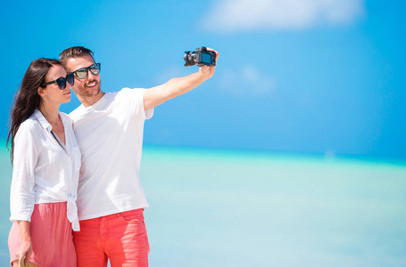 快乐的情侣在白色的沙滩上拍一张自拍的照片。两个成年人在热带风情海滩享受假期